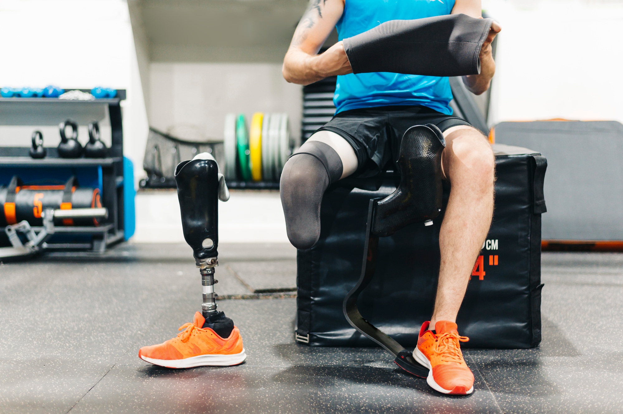 Disabled athlete assembling his leg prosthesis in the gym. Paralympic Sport Concept.